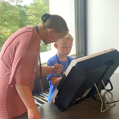 Employee helping her son vote using an ExpressVote during ES&S' Take Your Child To Work event.